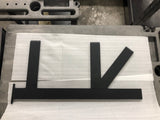 A Black Custom Support Bracket with two arms coming out horizontally at a 90-degree angle and one arm at a 45-degree angle, laying on packing paper on a concrete floor.