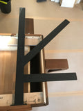 A Black Custom Support Bracket in a ‘K’ shape on a dark brown wooden countertop.