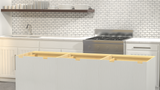 A white kitchen island showing five notches where the industrial Hidden Island Support Brackets would be placed with a white counter and stainless steel stove in the background.