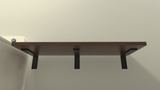 A front view of a dark wood shelf attached to a white wall with 3 black regular wood shelf brackets..