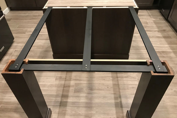 Squared-off Black Custom Support Brackets attached to a kitchen island with black column legs on a wooden floor.